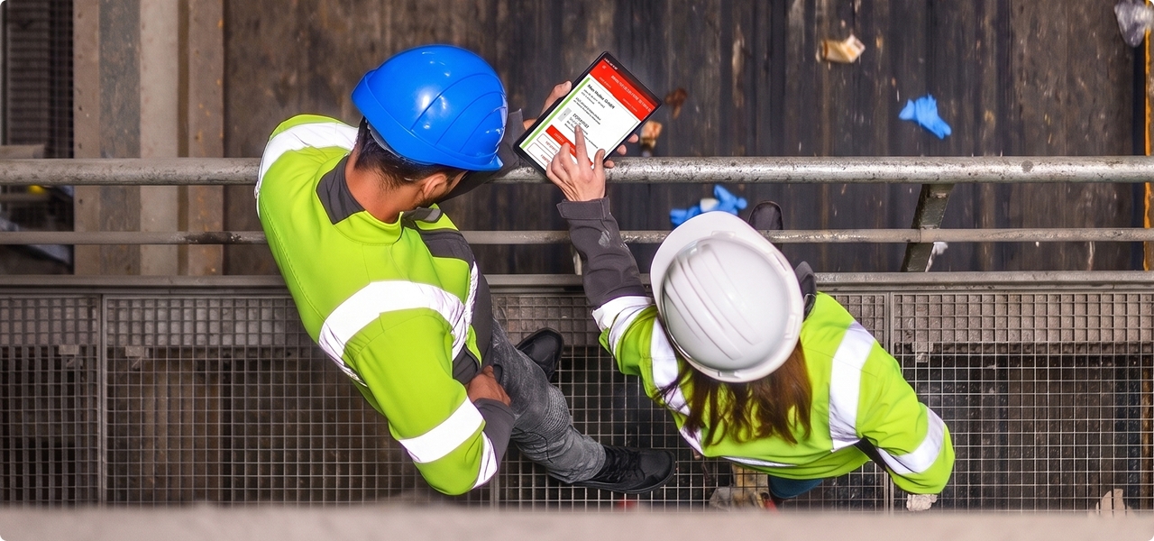 Zwei Personen überwachen eine Sortieranlage mit einem Tablet