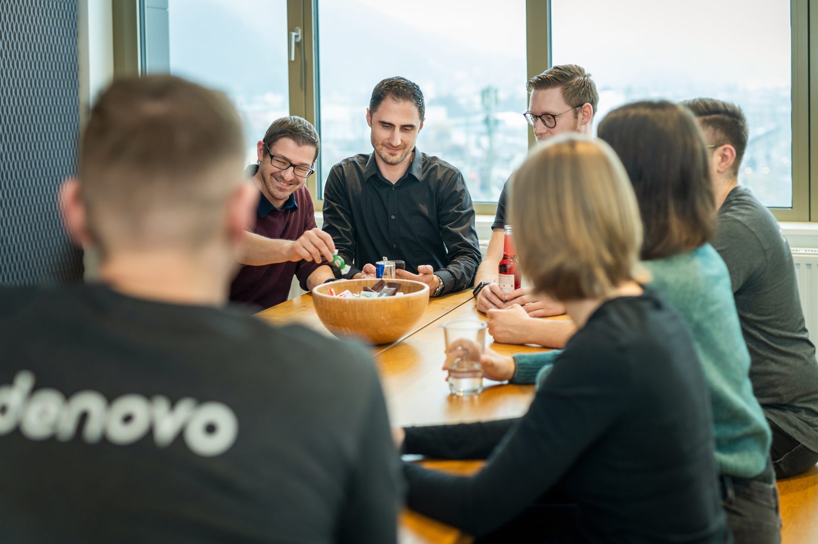 The team sits together at a table in the Denovo office