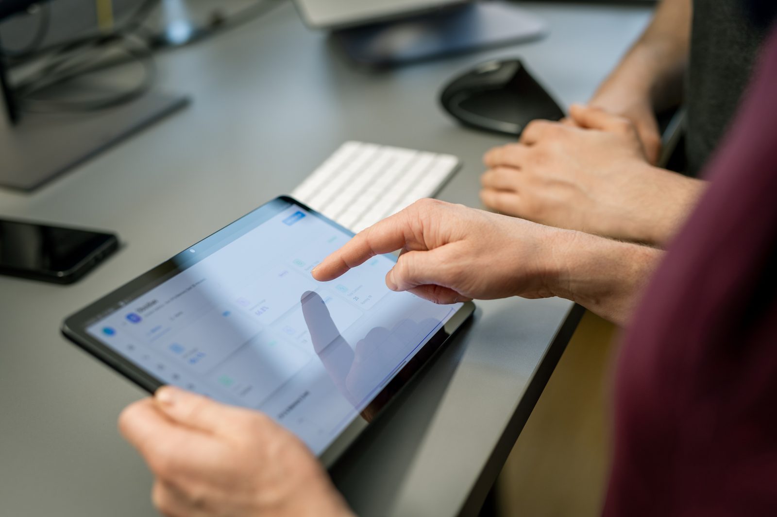 Teammitglieder arbeiten gemeinsam an einem Tablet