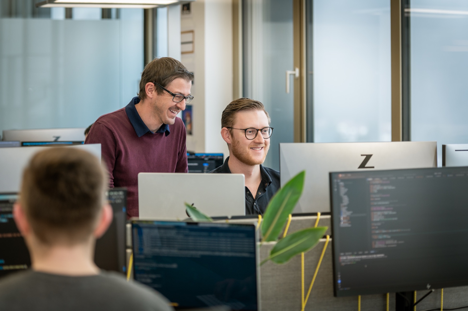 Team arbeitet gemeinsam an mehreren Computerarbeitsplätzen
