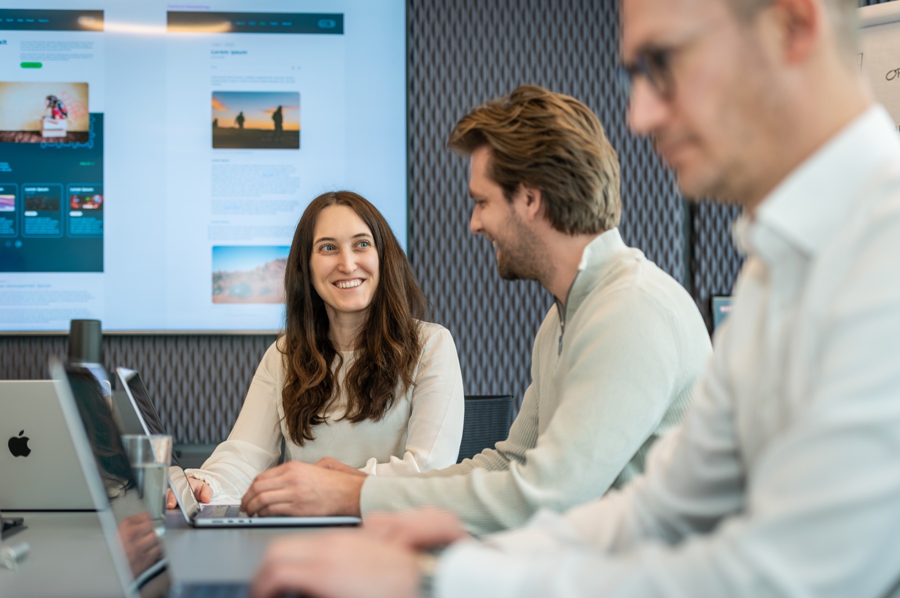 Three team members exchange ideas at a workstation