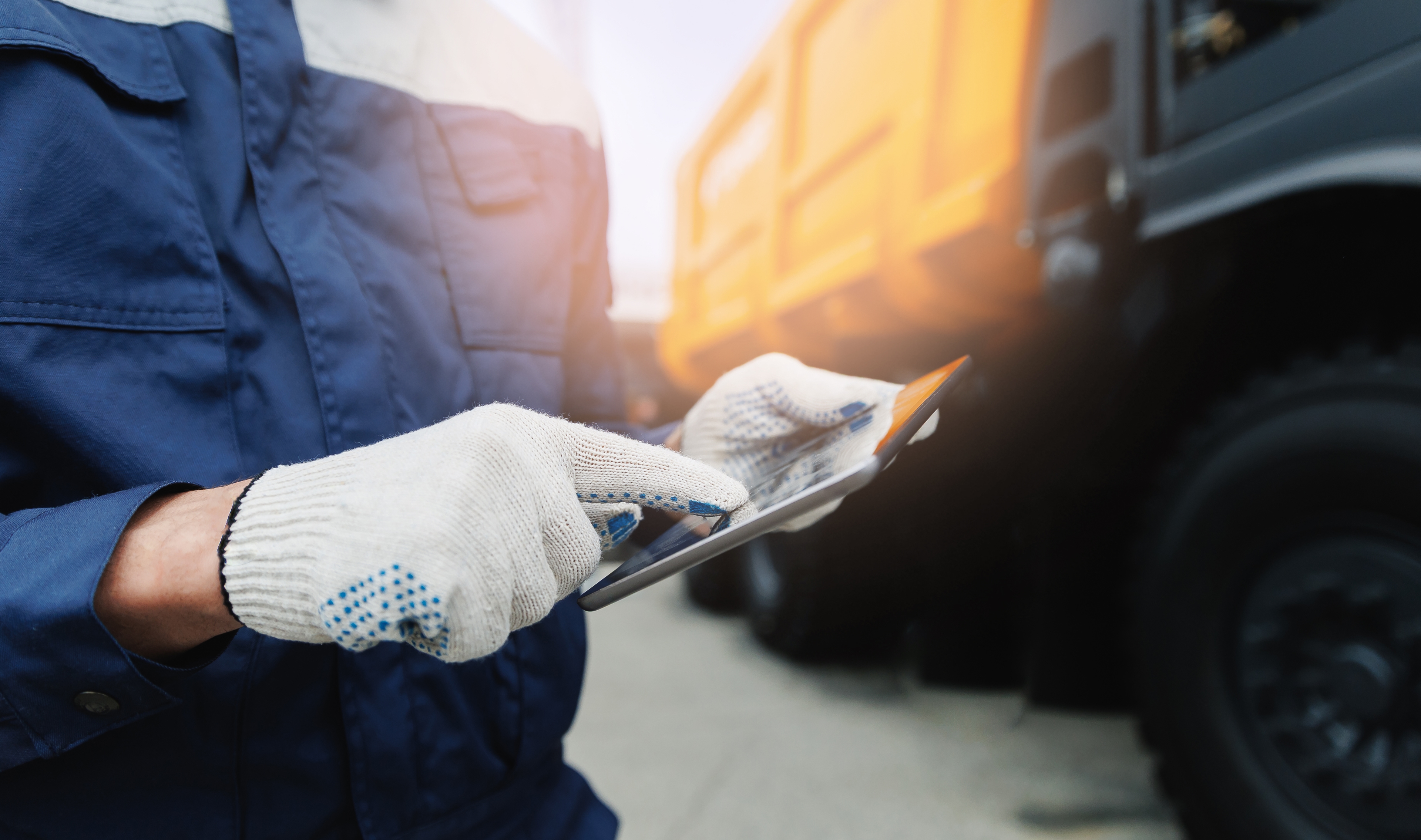 Person uses a tablet next to a waste collection vehicle